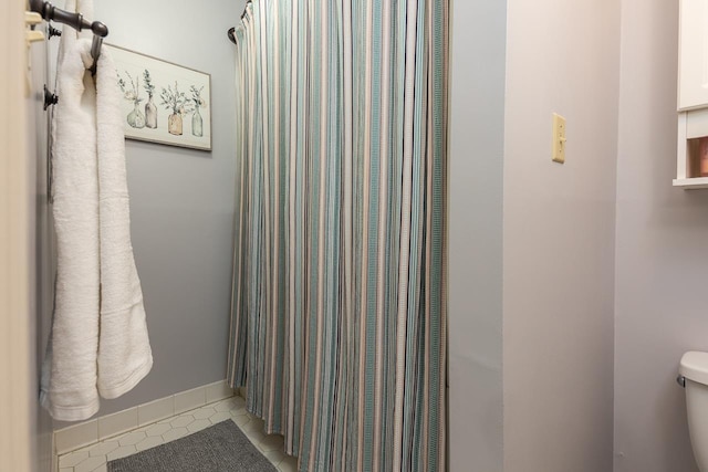 bathroom featuring toilet, a shower with curtain, and tile patterned floors