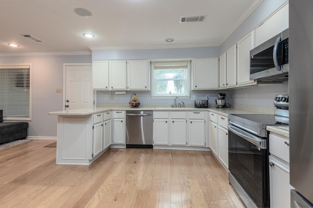 kitchen featuring crown molding, visible vents, appliances with stainless steel finishes, a sink, and a peninsula