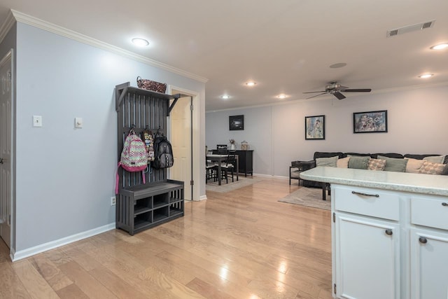 kitchen featuring a ceiling fan, visible vents, light wood-style floors, light countertops, and crown molding