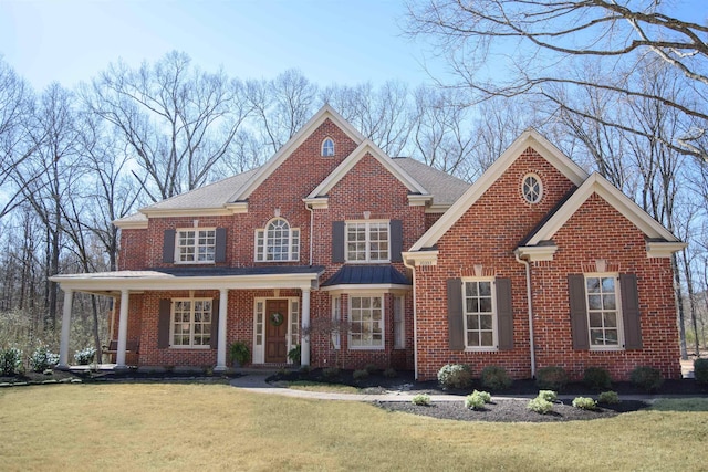 view of front of house with brick siding, a porch, and a front yard