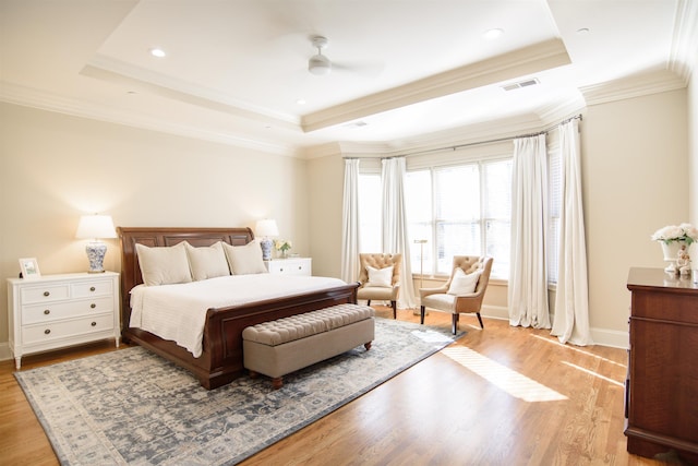 bedroom featuring a tray ceiling, visible vents, and light wood finished floors