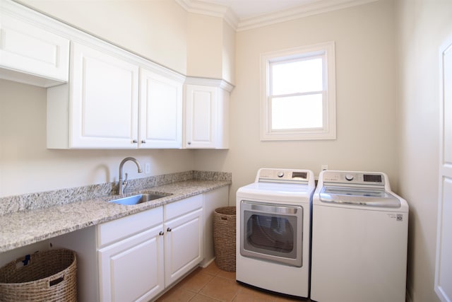 washroom with light tile patterned floors, a sink, ornamental molding, cabinet space, and washing machine and clothes dryer