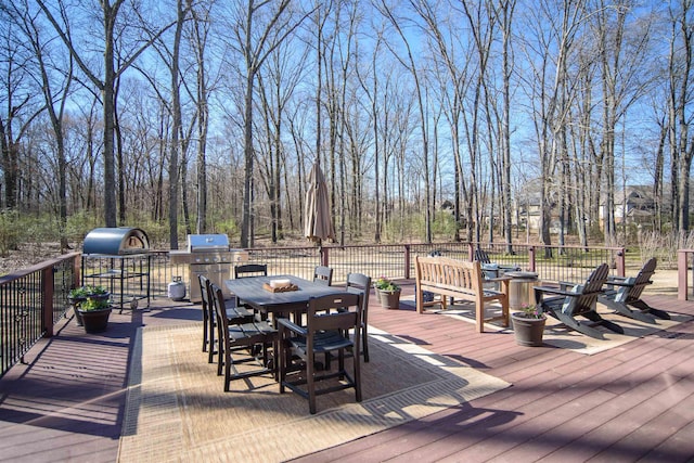 wooden terrace with outdoor dining space and a grill