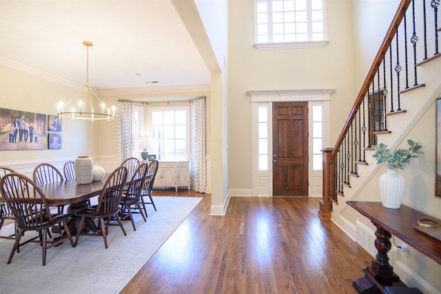 entrance foyer with baseboards, wood finished floors, an inviting chandelier, stairs, and crown molding