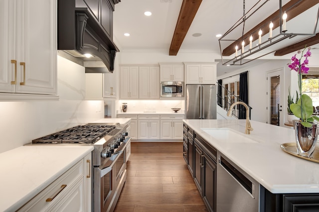 kitchen with premium appliances, dark wood-type flooring, beamed ceiling, light countertops, and a sink