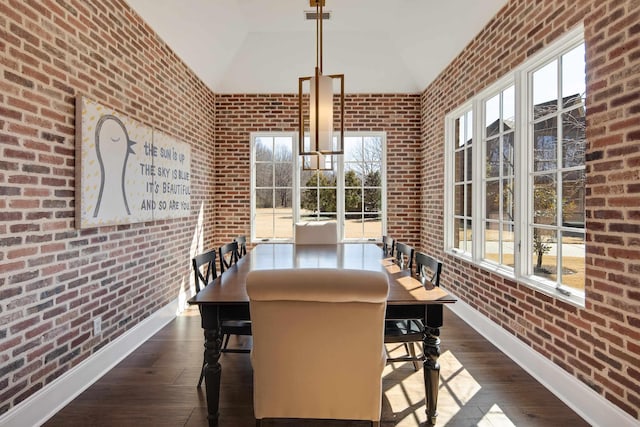 dining space with dark wood-style floors, brick wall, and a healthy amount of sunlight