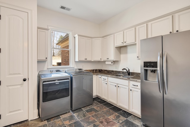 clothes washing area featuring a sink, visible vents, independent washer and dryer, cabinet space, and stone finish floor