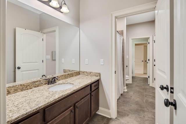 bathroom featuring toilet, curtained shower, baseboards, and vanity