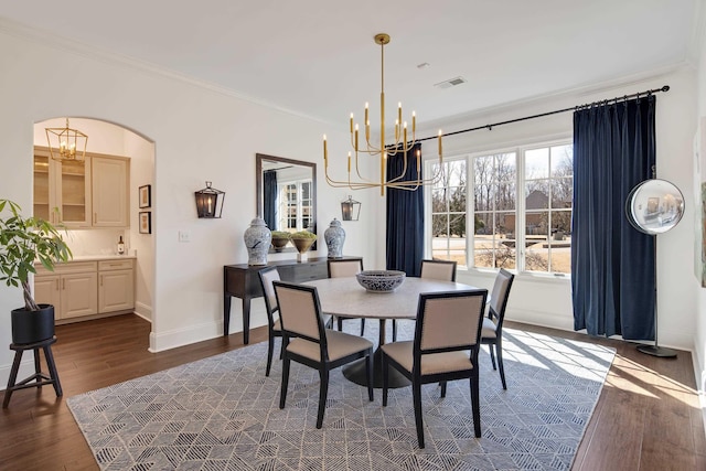 dining area featuring dark wood-style floors, visible vents, an inviting chandelier, and ornamental molding