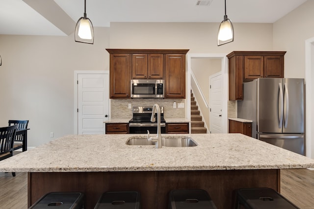 kitchen with appliances with stainless steel finishes, a breakfast bar area, backsplash, and decorative light fixtures