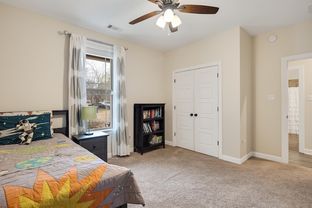 bedroom featuring a closet, light colored carpet, ceiling fan, and baseboards