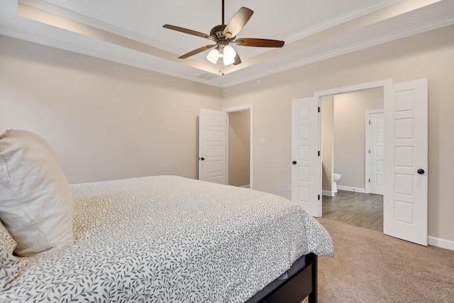 bedroom with ornamental molding, a tray ceiling, baseboards, and carpet