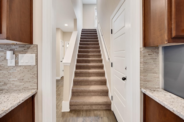 stairway with baseboards, wood finished floors, and recessed lighting