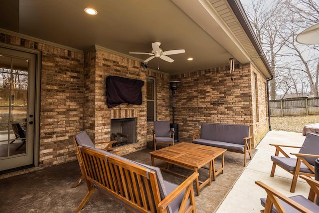 view of patio with ceiling fan, an outdoor living space with a fireplace, and fence