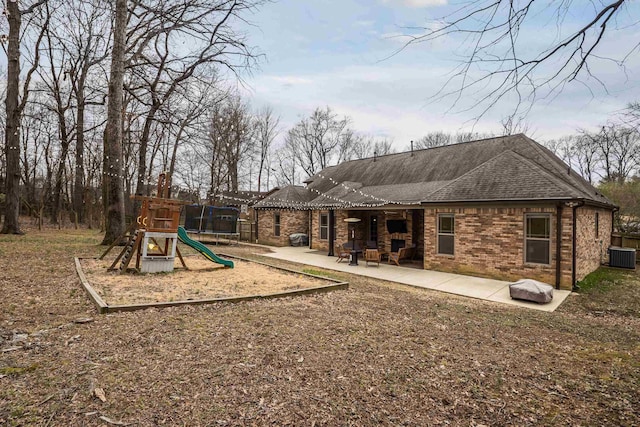 back of property featuring a patio, a playground, cooling unit, brick siding, and a shingled roof