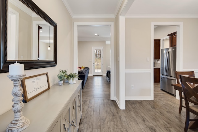 corridor with ornamental molding, baseboards, and wood finished floors