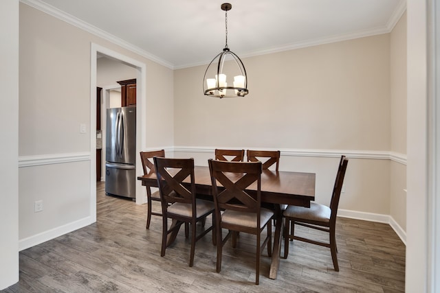 dining area featuring a chandelier, crown molding, wood finished floors, and baseboards