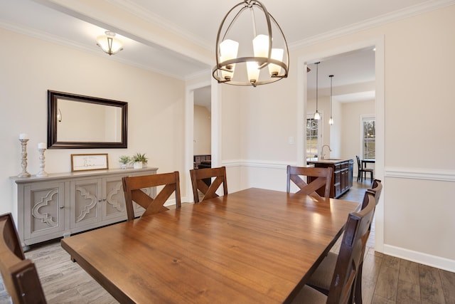 dining area with ornamental molding, an inviting chandelier, wood finished floors, and baseboards