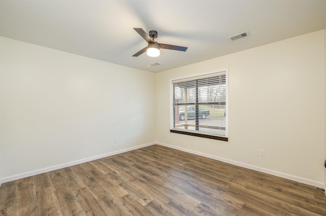 unfurnished room featuring dark wood-style floors, visible vents, baseboards, and a ceiling fan