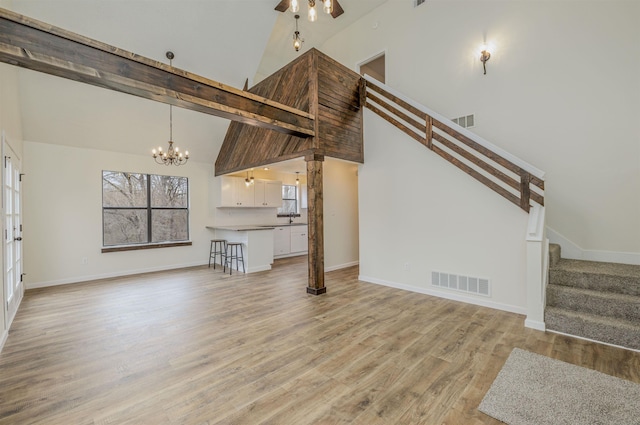 unfurnished living room featuring baseboards, stairway, visible vents, and light wood-style floors