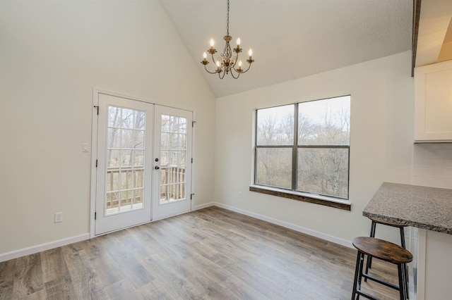 unfurnished dining area with a healthy amount of sunlight, light wood-style floors, baseboards, and french doors