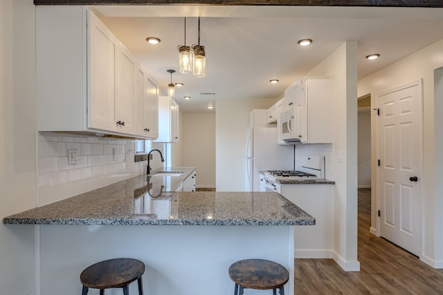 kitchen with stone counters, dark wood-type flooring, white cabinets, white appliances, and a kitchen breakfast bar