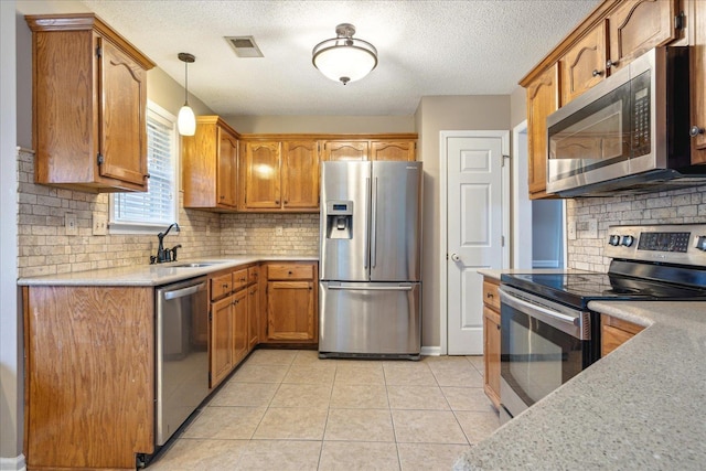 kitchen with visible vents, brown cabinets, stainless steel appliances, light countertops, and a sink