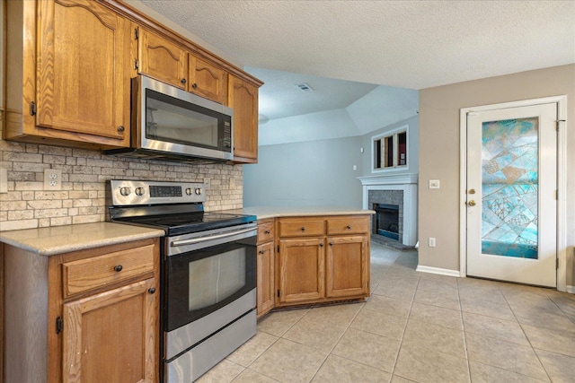 kitchen featuring brown cabinets, appliances with stainless steel finishes, light countertops, and backsplash