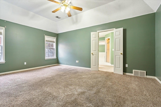 spare room with visible vents, baseboards, lofted ceiling, ceiling fan, and carpet