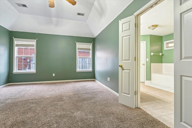 unfurnished room featuring lofted ceiling, light colored carpet, a ceiling fan, baseboards, and visible vents