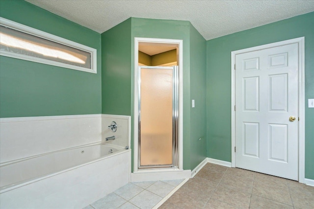 bathroom featuring a garden tub, a textured ceiling, tile patterned flooring, and a shower stall