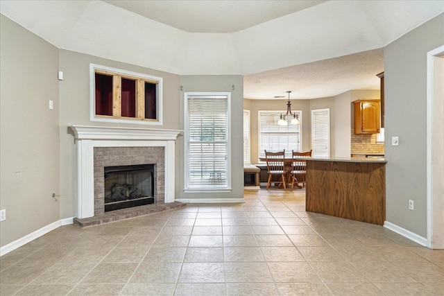 living area featuring light tile patterned floors, a fireplace, and baseboards