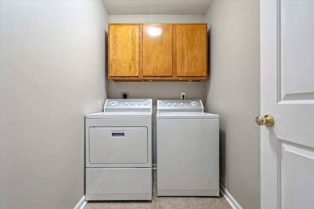 laundry room featuring light tile patterned floors, a textured ceiling, baseboards, independent washer and dryer, and cabinet space