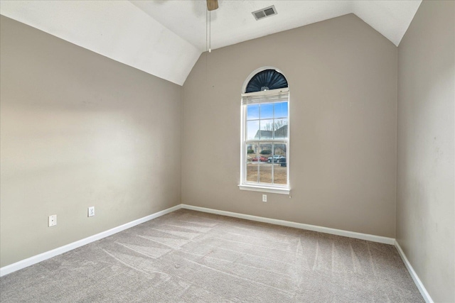 carpeted empty room with vaulted ceiling, a ceiling fan, visible vents, and baseboards