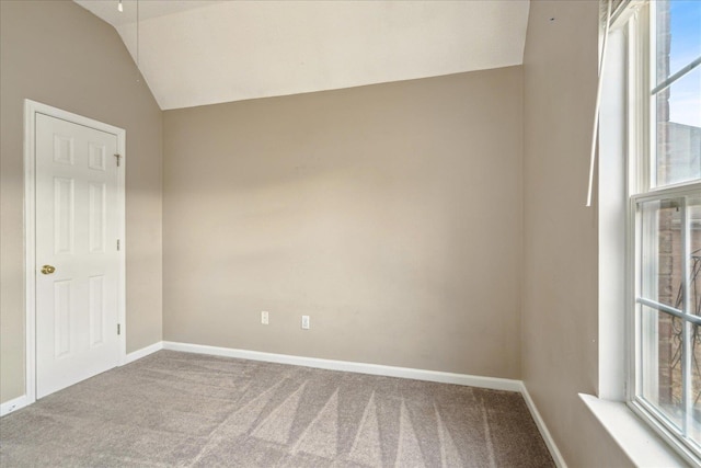 carpeted spare room featuring baseboards and vaulted ceiling