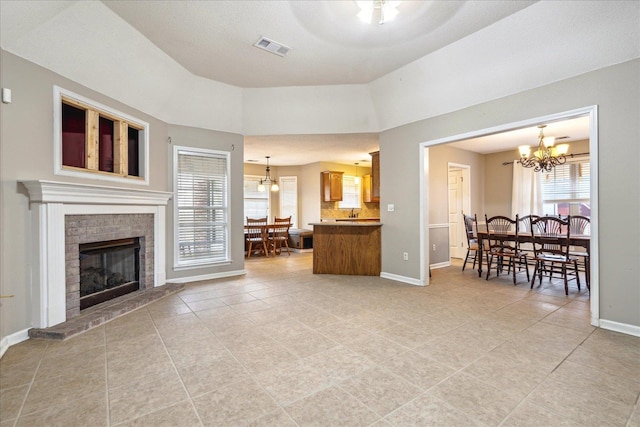 living area with a chandelier, light tile patterned flooring, visible vents, baseboards, and a brick fireplace