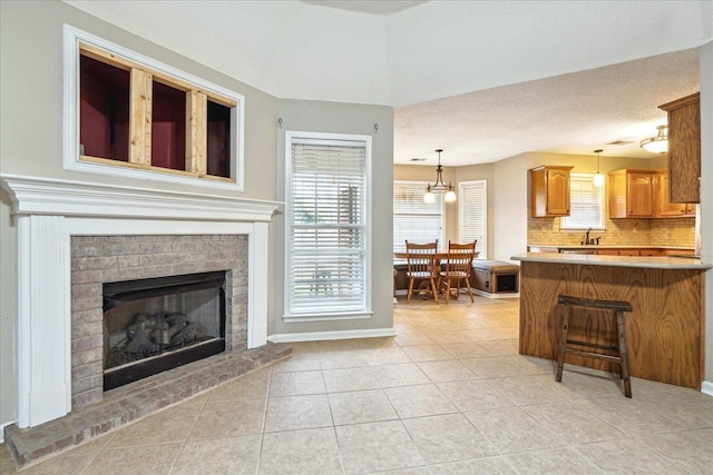 living area with a fireplace, baseboards, a textured ceiling, and light tile patterned flooring