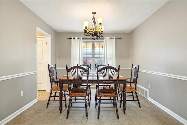 dining space featuring a textured ceiling, light tile patterned flooring, a notable chandelier, visible vents, and baseboards