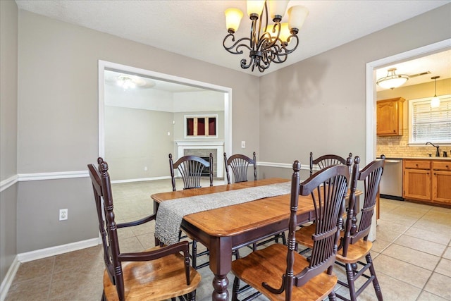 dining area with light tile patterned floors, baseboards, a textured ceiling, a fireplace, and a notable chandelier