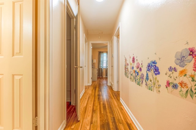 corridor featuring light wood-type flooring and baseboards