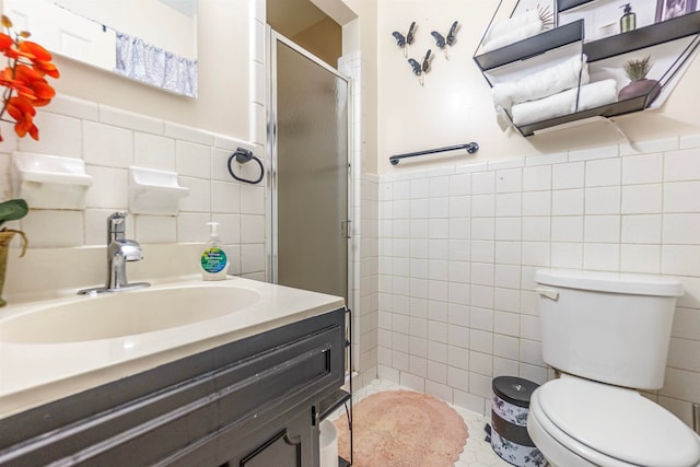 bathroom with toilet, vanity, tile walls, wainscoting, and a shower stall