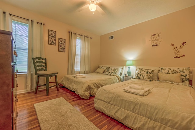 bedroom with ceiling fan, visible vents, and wood finished floors