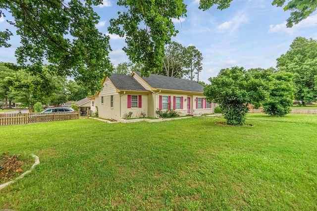 ranch-style home with a front yard, brick siding, and fence