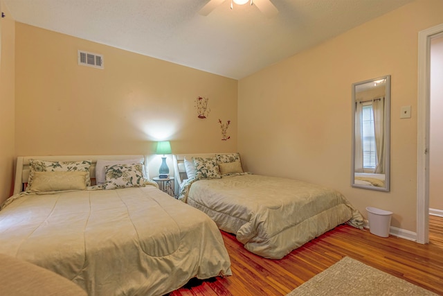 bedroom with lofted ceiling, wood finished floors, visible vents, baseboards, and a ceiling fan