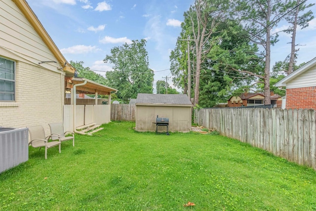 view of yard with an outbuilding, a storage shed, central AC unit, and a fenced backyard