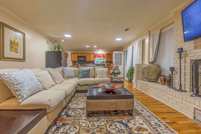 living area with recessed lighting, visible vents, crown molding, and wood finished floors