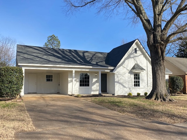 view of front facade featuring driveway, roof with shingles, and brick siding