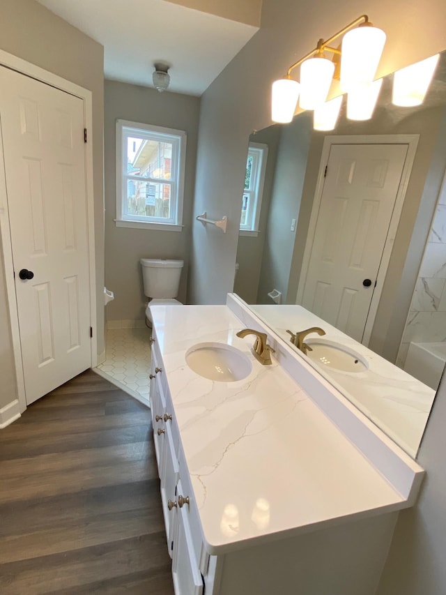 bathroom featuring toilet, baseboards, wood finished floors, and vanity