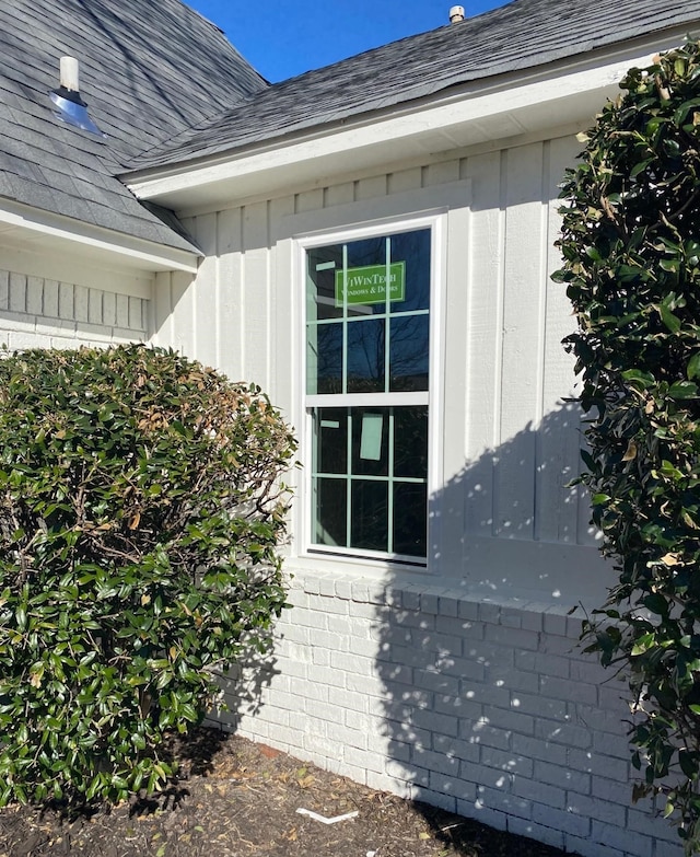 view of property exterior featuring a shingled roof and brick siding