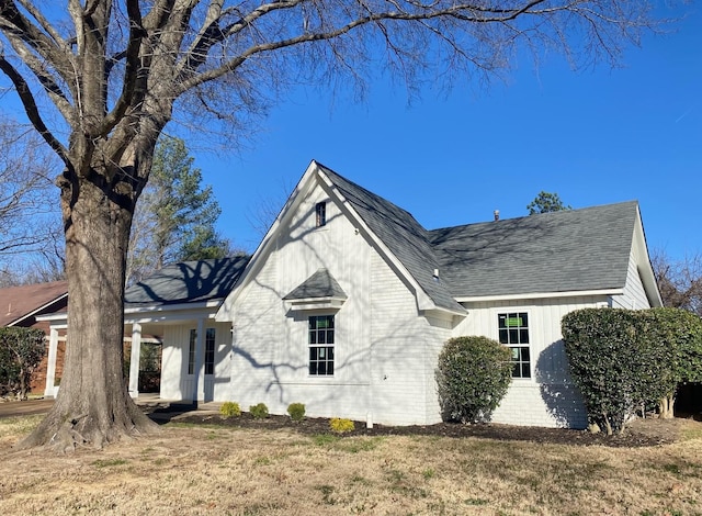 view of front of house featuring a shingled roof, a front yard, and brick siding